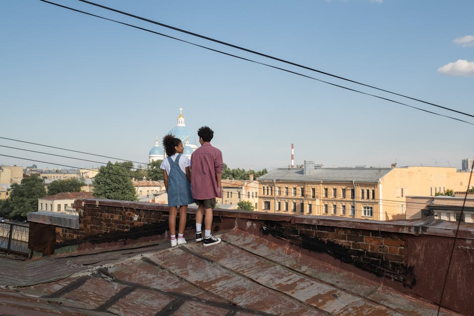 Un couple se tient sur un toit, profitant d'une vue panoramique sur la ville sous un ciel clair, symbolisant une expérience mémorable.