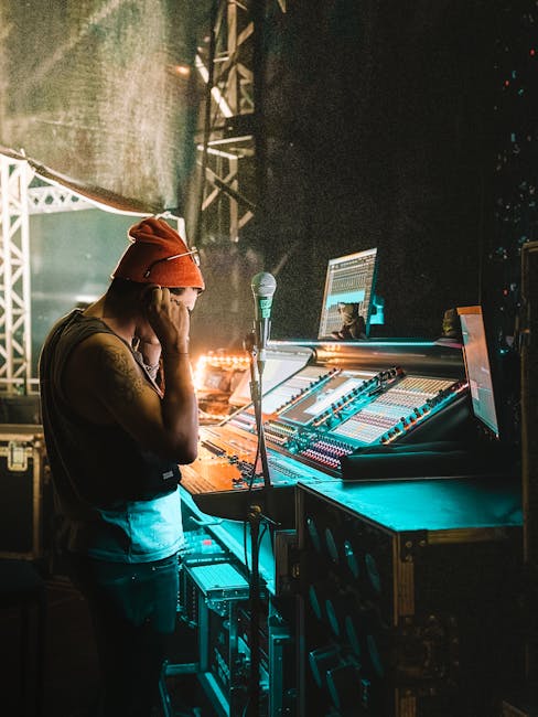 Support technique événementiel nocturne Backstage view of a sound technician managing audio controls during a live concert performance.