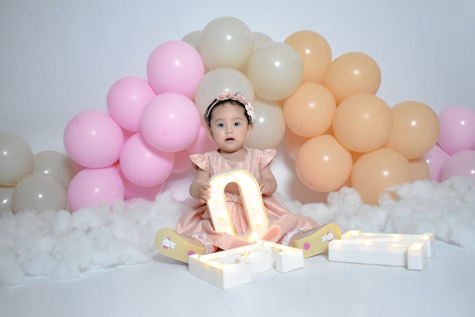 Cute baby sitting with colorful balloons and letter lights, perfect for celebrations.
