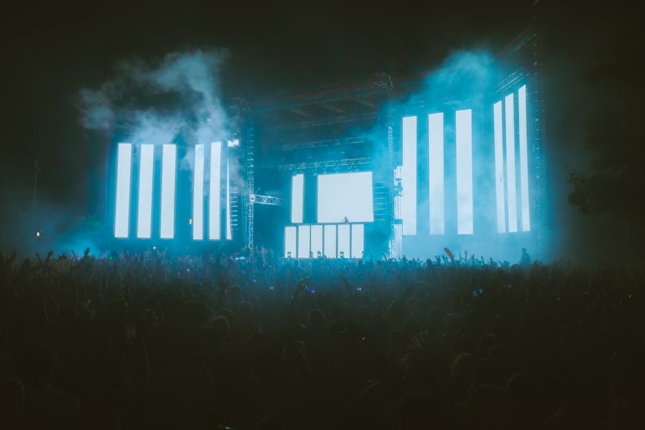 Energetic crowd at night music festival featuring large LED screens and colorful lighting effects.